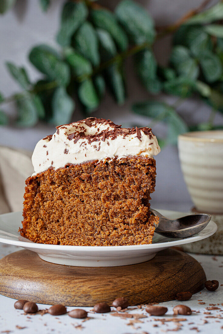 A slice of coffee cake that is topped with whipped cream and grated chocolate