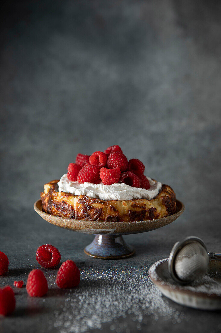 Basque Cheesecake with Whipped Cream and Raspberries on Dark Neutral Background