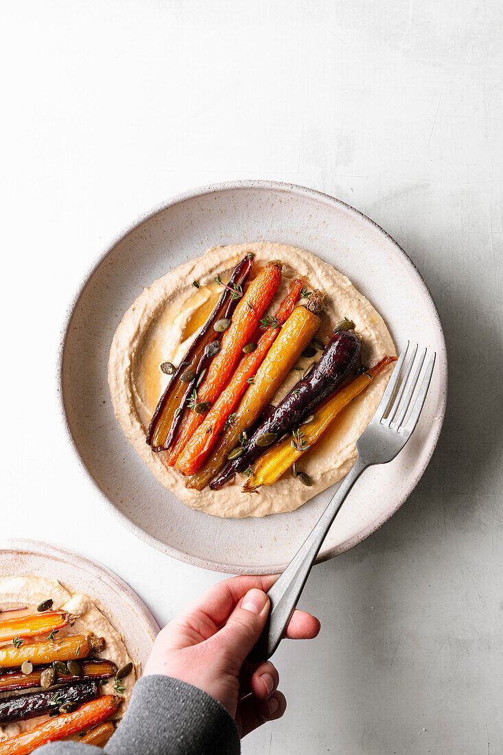 Honey roasted carrots with hummus in a ceramic bowl