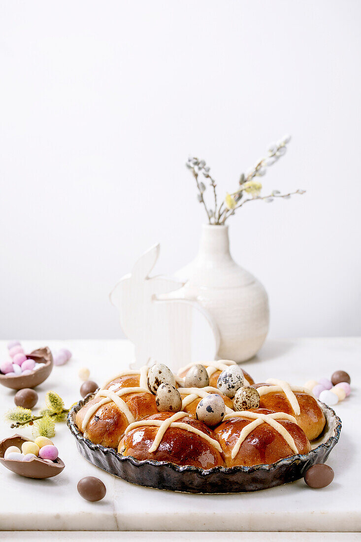 Hot Cross Buns dekoriert mit Wachteleiern auf Ostertisch