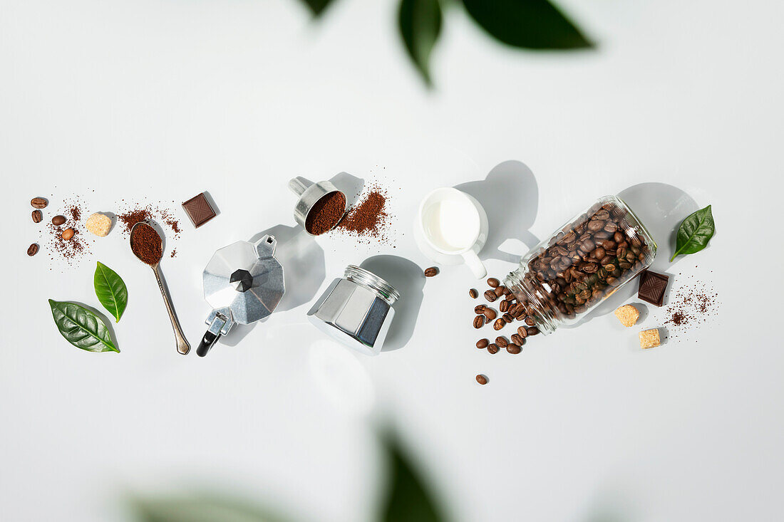 Coffee composition on light grey background with green branches, flat lay, top view