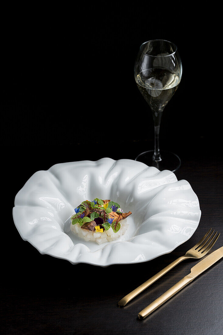 Appetizing scallop tartare decorated with greens and flowers