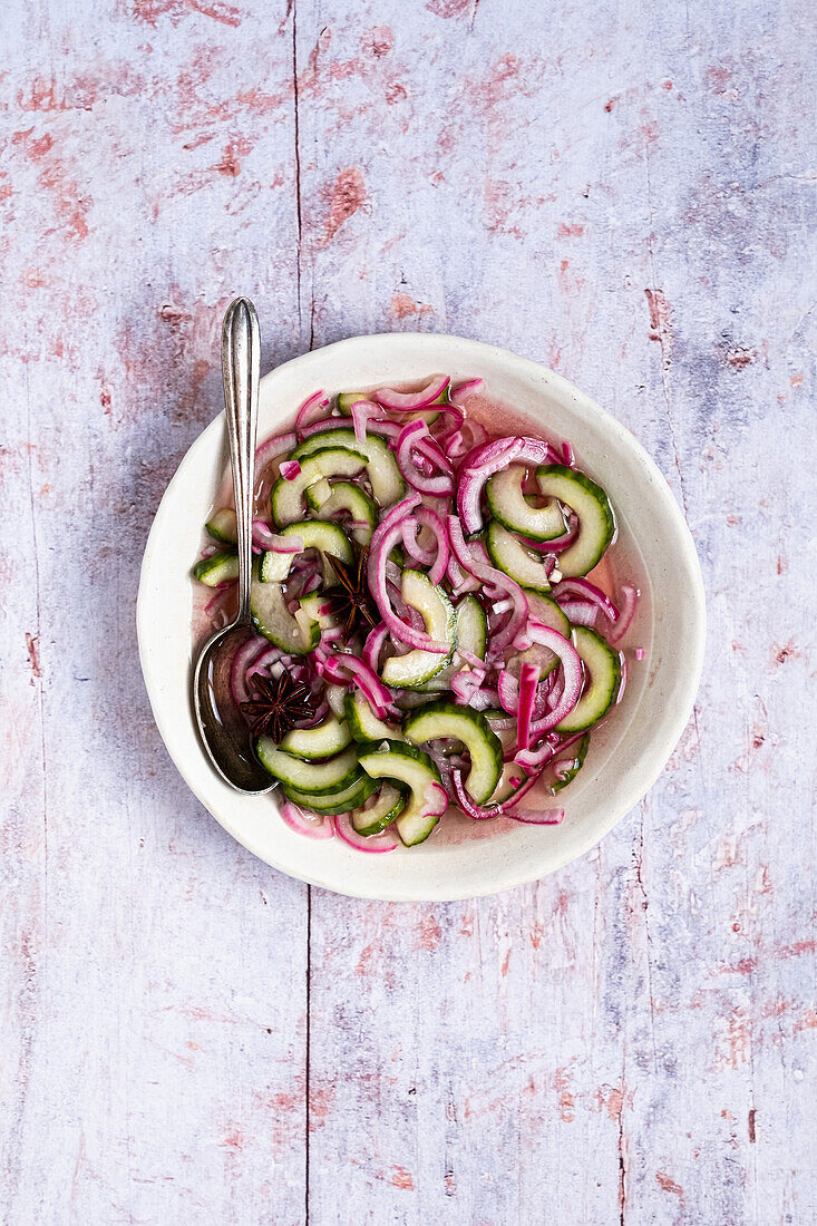 Ttasty onion and cucumber salad with oily sauce and spoon on shabby table