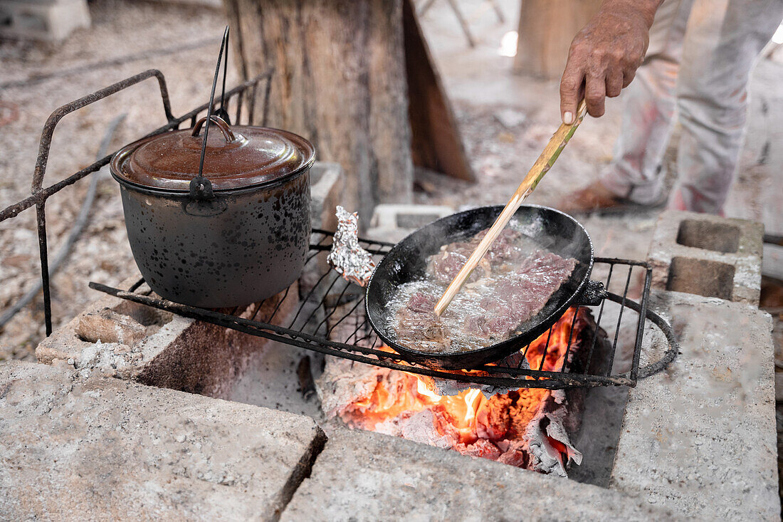 Rindfleisch wird in Pfanne über offenem Feuer gebraten