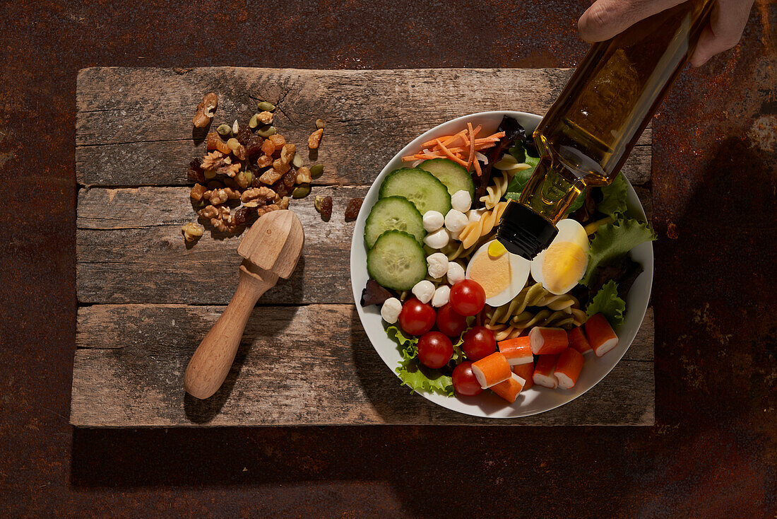 Fresh salad with vegetables and eggs placed on rusty table near lemon reamer on cutting board