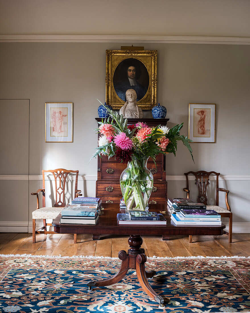 Antiker Tisch mit Büchern und Blumenstrauß vor Kommode, ägyptischer Teppich im Salon