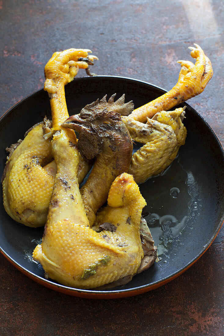 Chicken with head and feet in a pan
