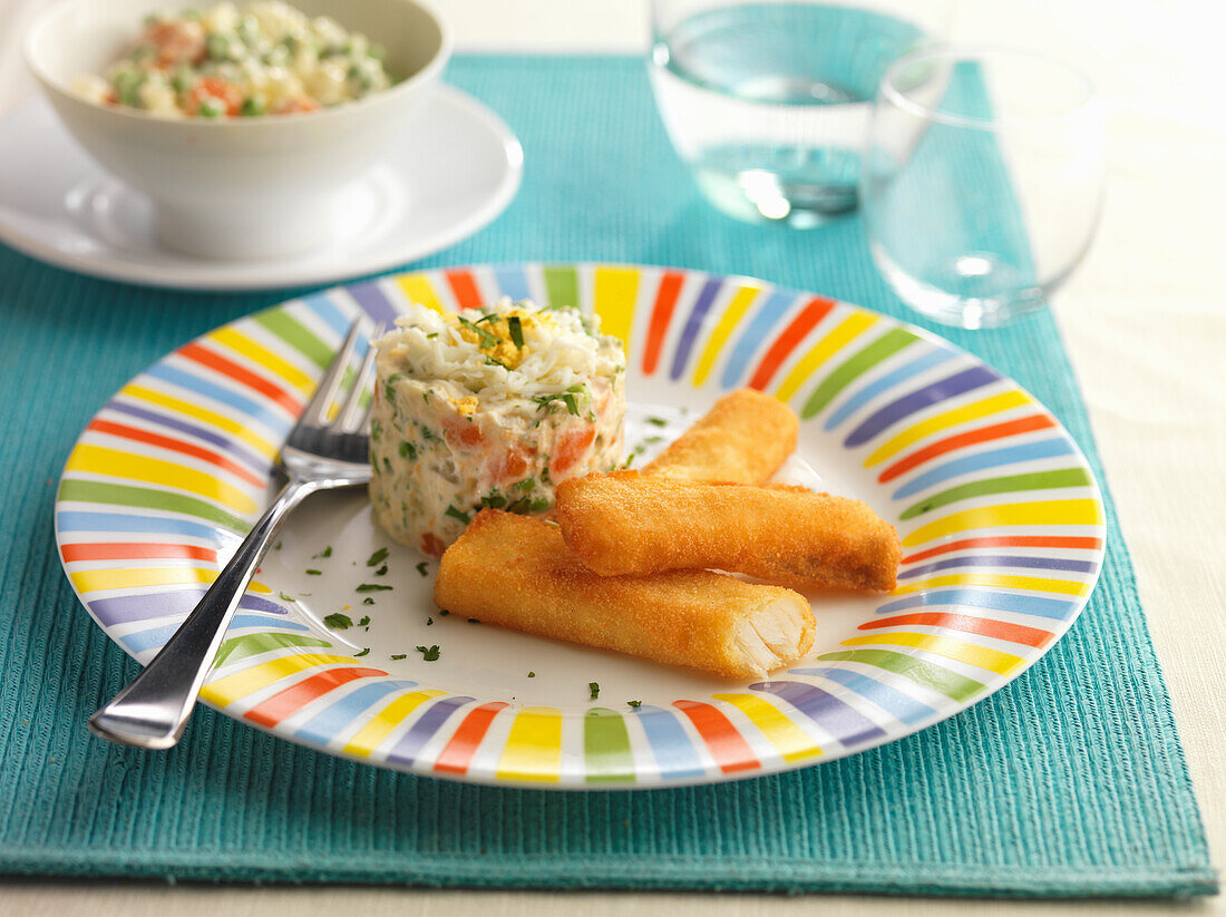 Breaded hake fillets on a colorful plate