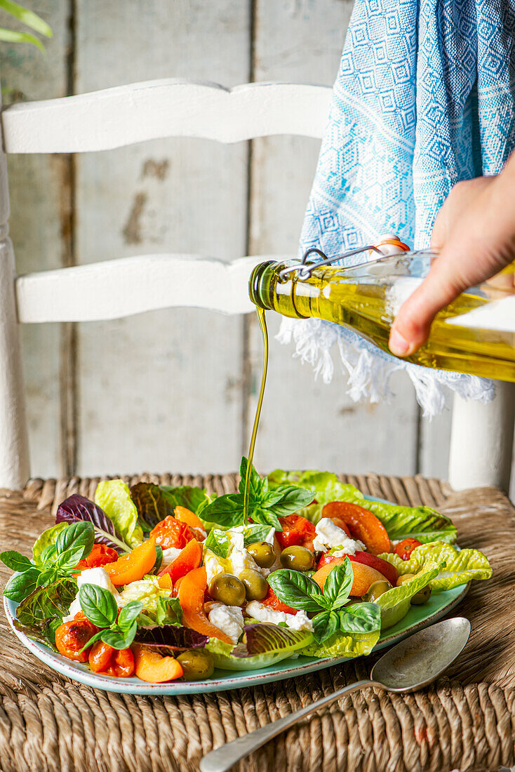 Summer salad with fresh apricots, mozzarella cheese, olives, roasted tomatoes, basil and olive oil