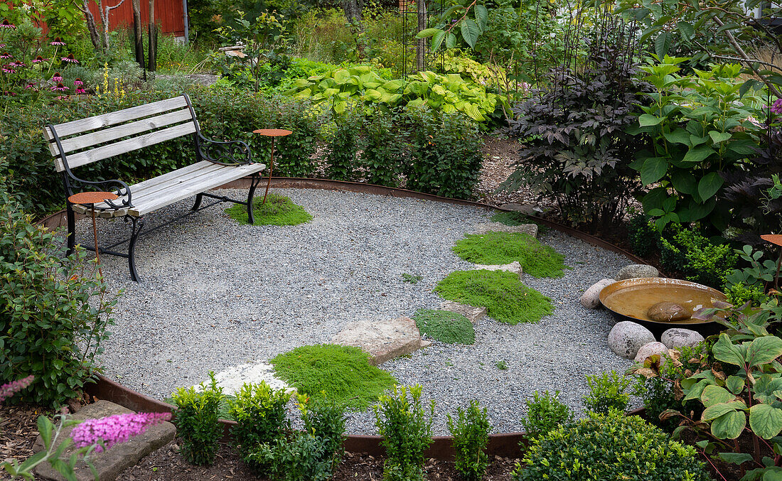 Ovaler Kiesplatz mit Sitzbank im Garten