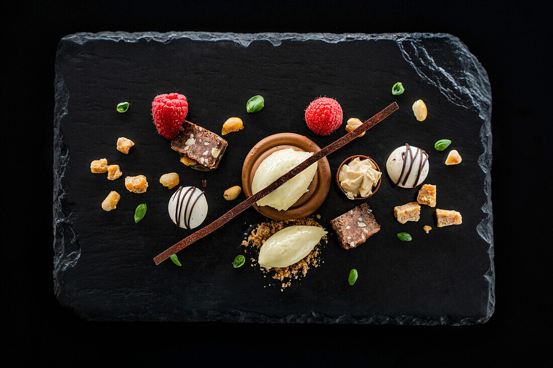 Dessert with chocolate, raspberries and ice cream on a black slate platter