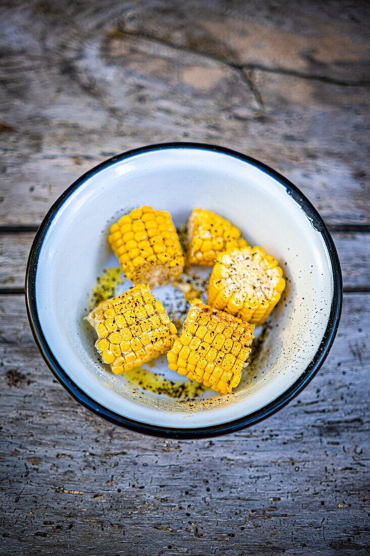 Grilled corn with spices in an enamel bowl
