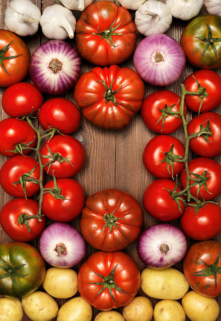 Tomatoes, onions and potatoes arranged around the edge of the picture