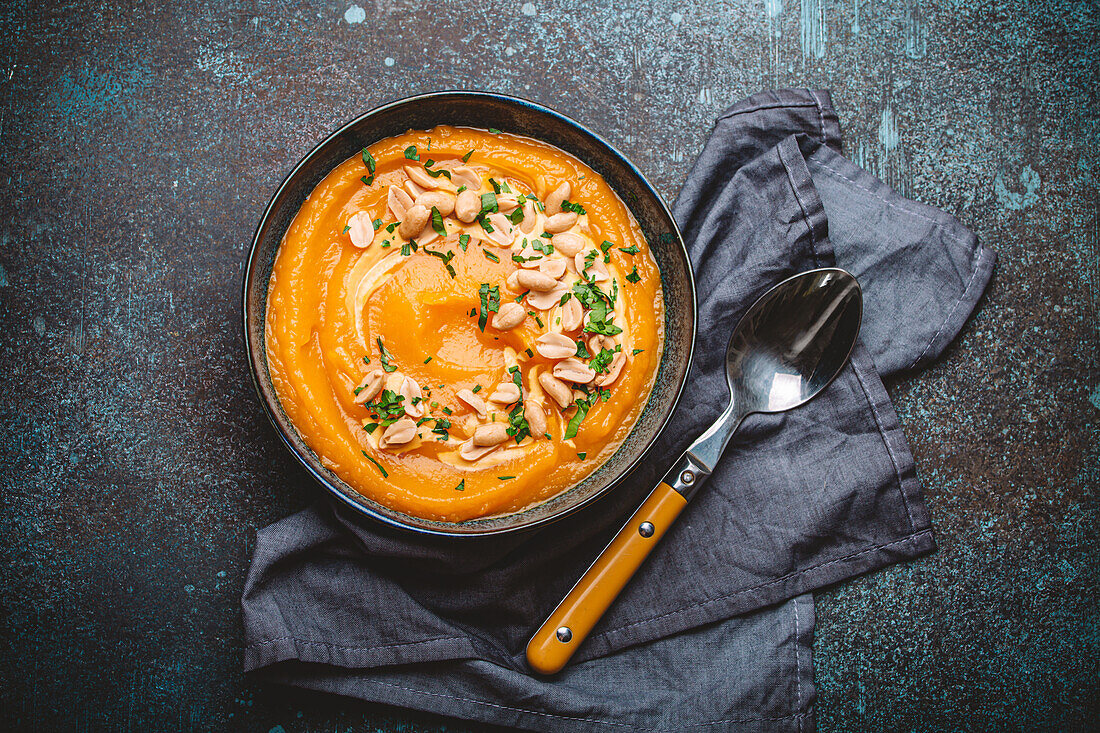 Kürbiscremesuppe bestreut mit Erdnüssen in Keramikschale