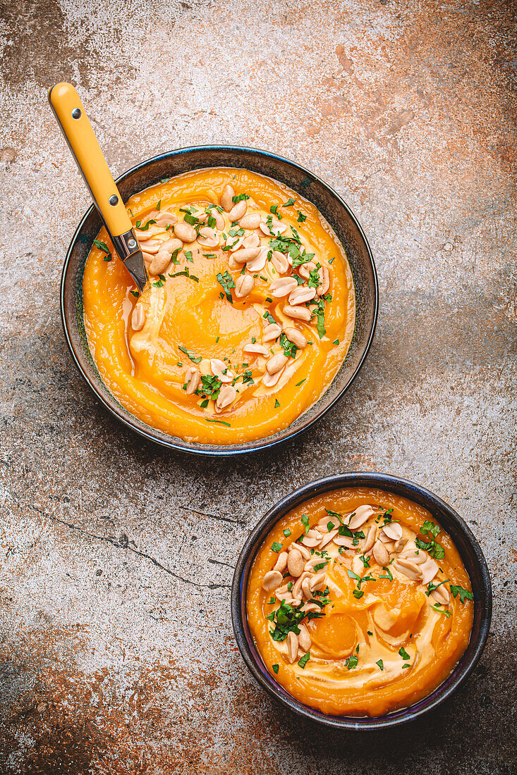 Cream of pumpkin soup sprinkled with peanuts in two ceramic bowls