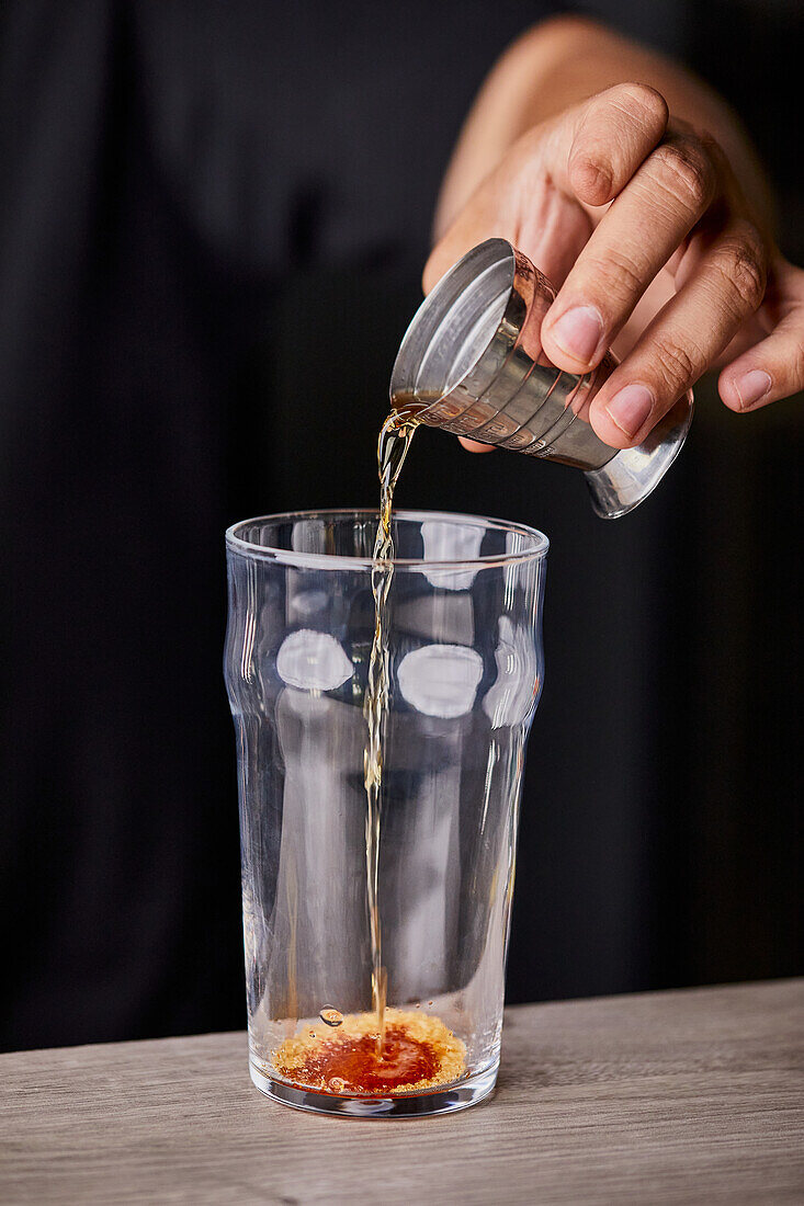 Making Old Fashioned cocktail, pouring bitter liquor in a glass