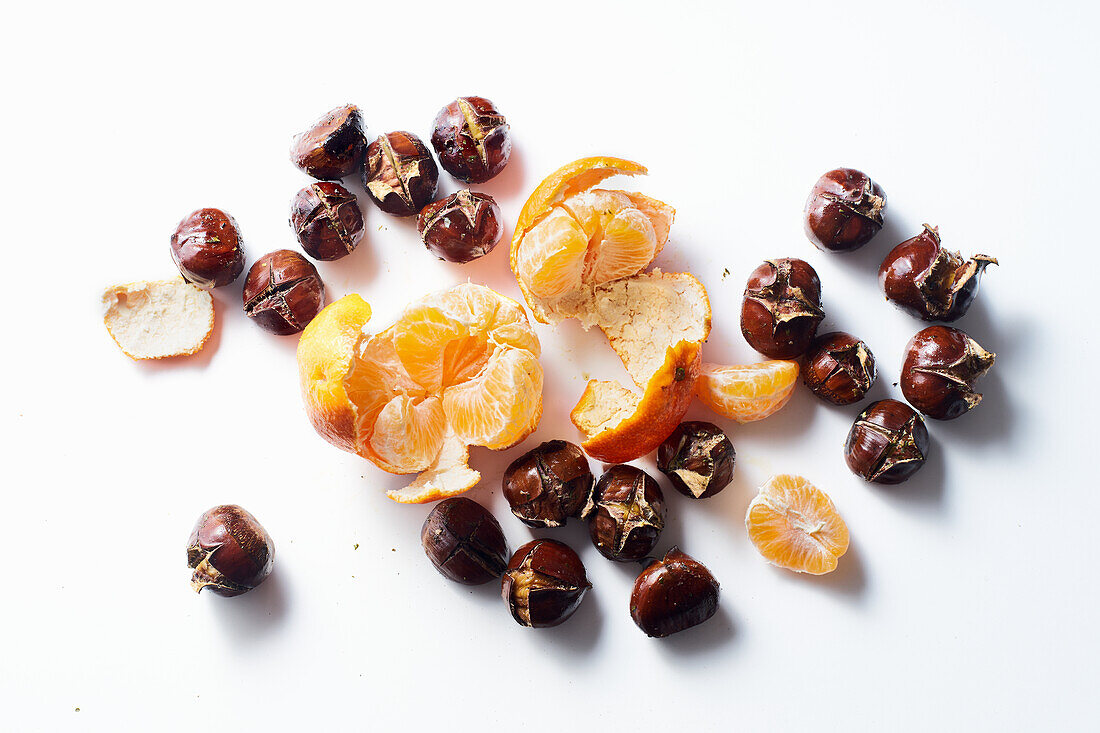 Flat lay with roasted chestnuts and clementines on white background