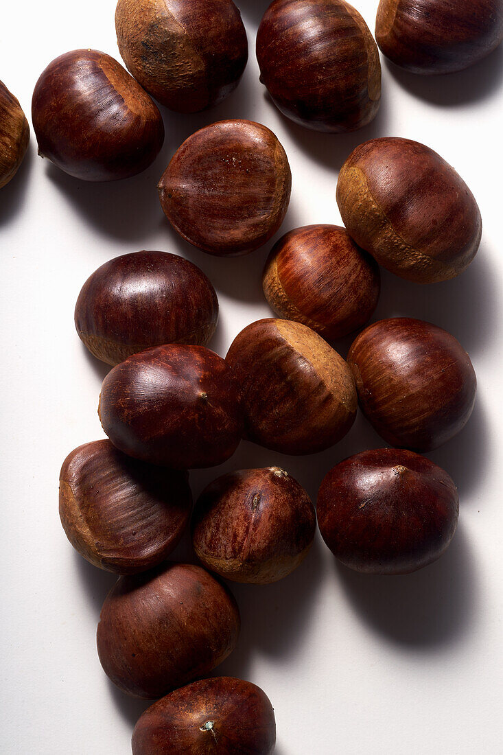 Raw, uncooked chestnuts on a white background