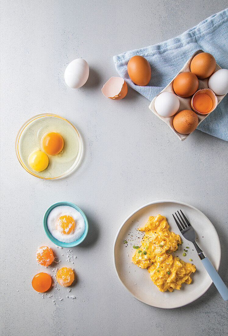 Scrambled eggs next to fresh eggs and frozen egg yolk with salt