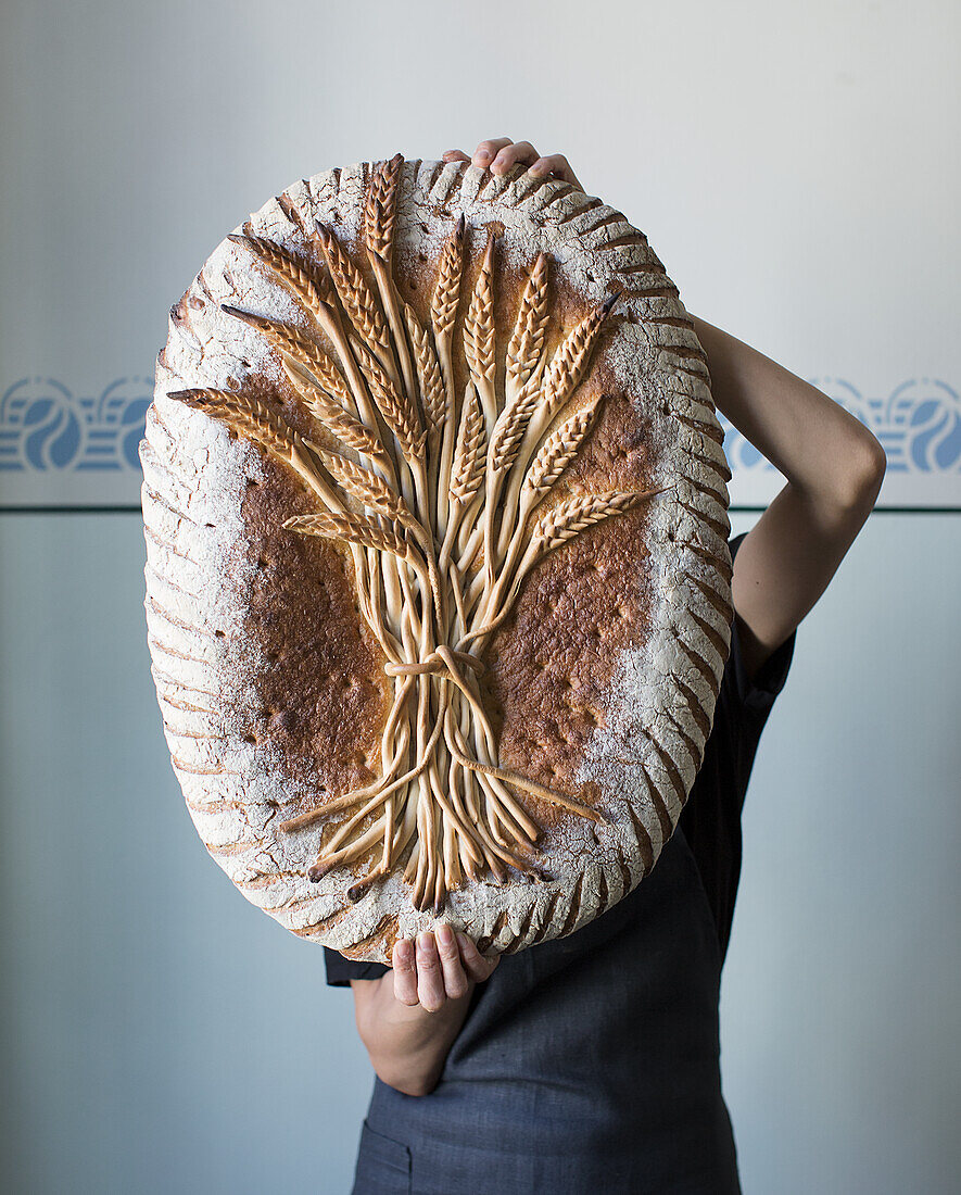 A person holding decorative bread