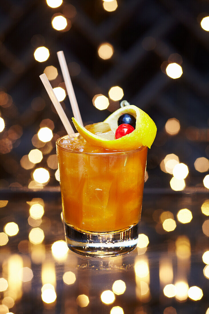 Festlicher Weihnachtscocktail mit Whisky und Orangen, garniert mit Orangenschale und Früchten