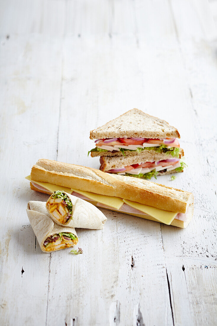 Selection of deli wraps, baguette and sandwhiches filled with chicken and salad, ham and cheese, tomatoes, onion and cheese