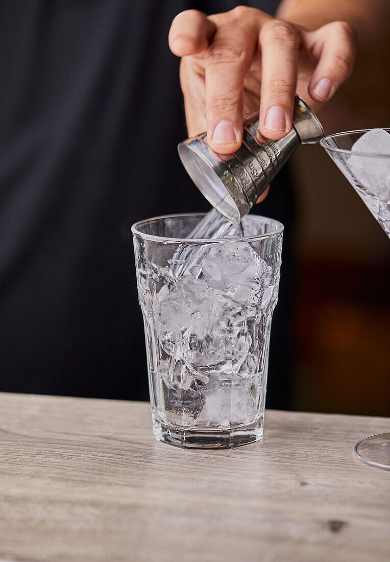 Cosmopolitan-Cocktail zubereiten: Wodka in ein Glas gießen