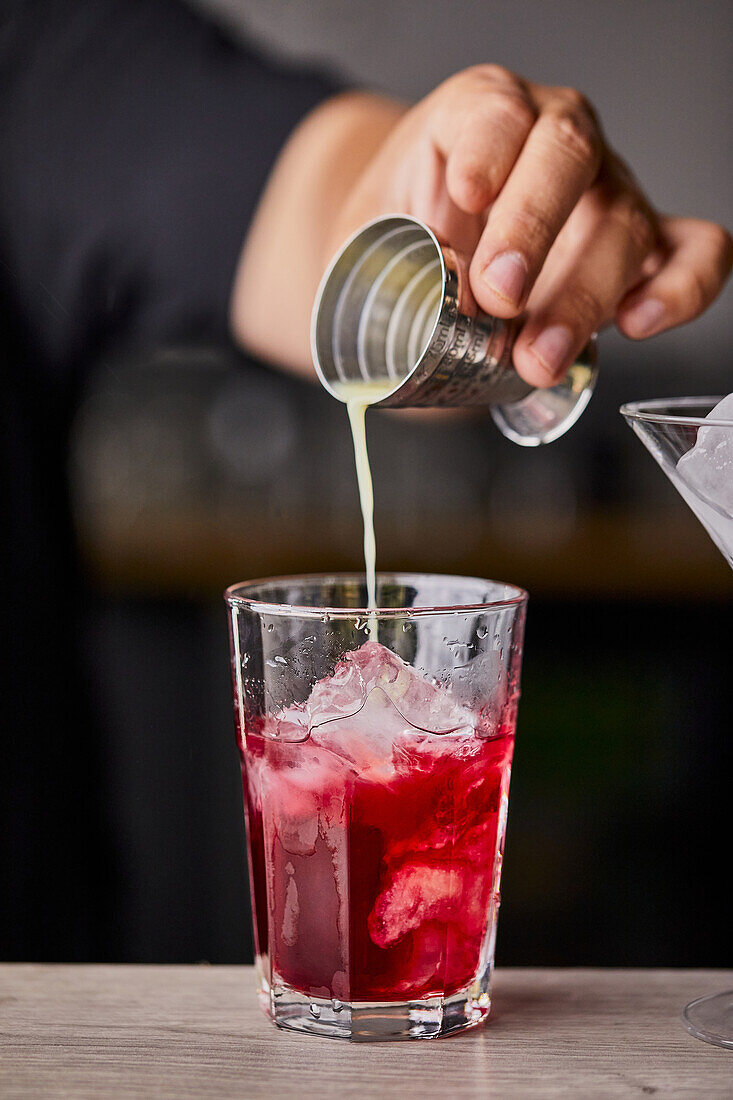 Cosmopolitan-Cocktail zubereiten: Limettensaft in ein Glas gießen