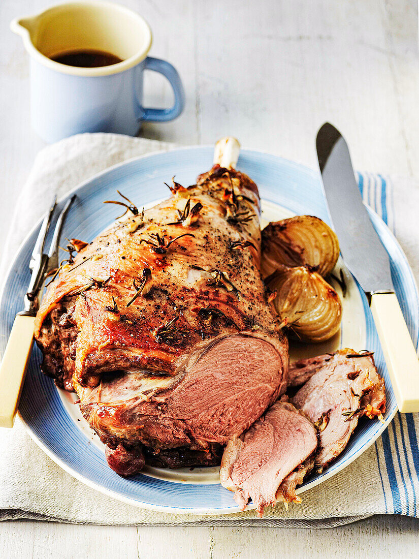 Roasted leg of lamb with roasted onions and rosemary, served with sauce