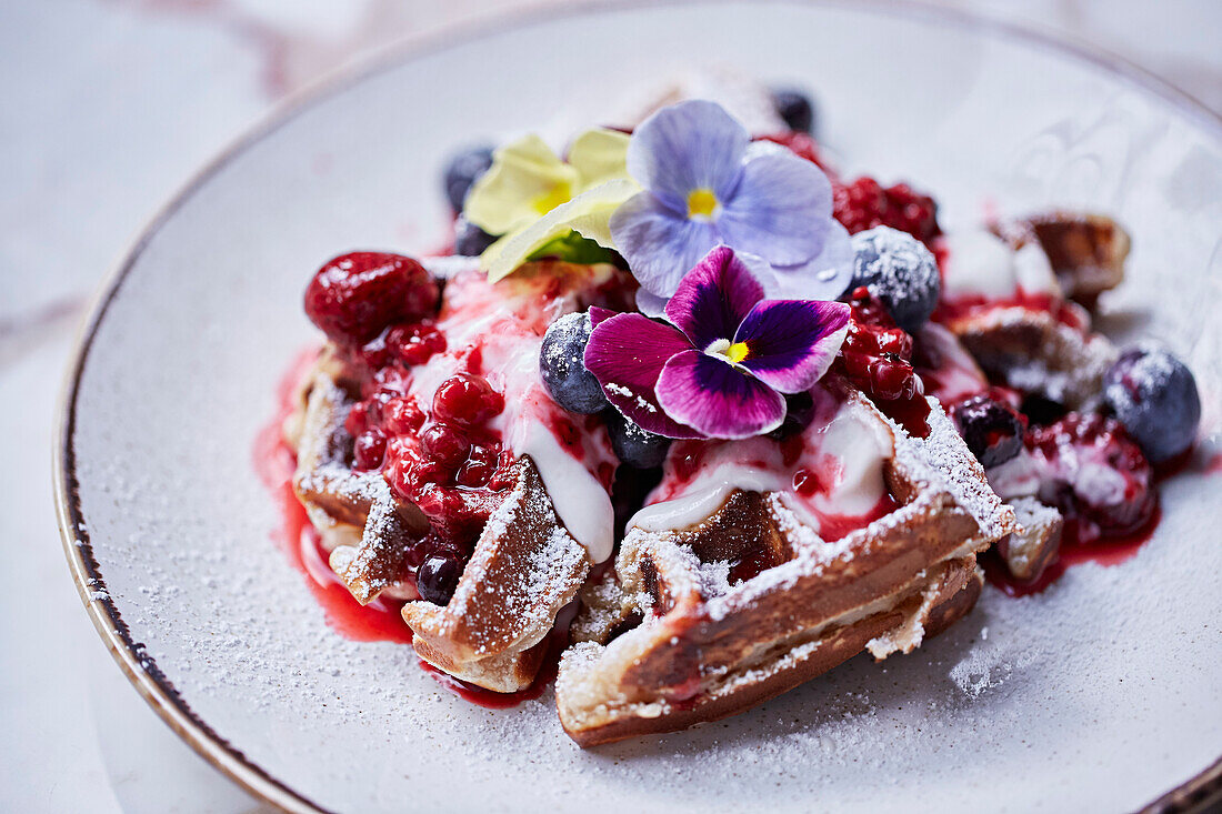 Waffles with berries, yogurt, and flowers
