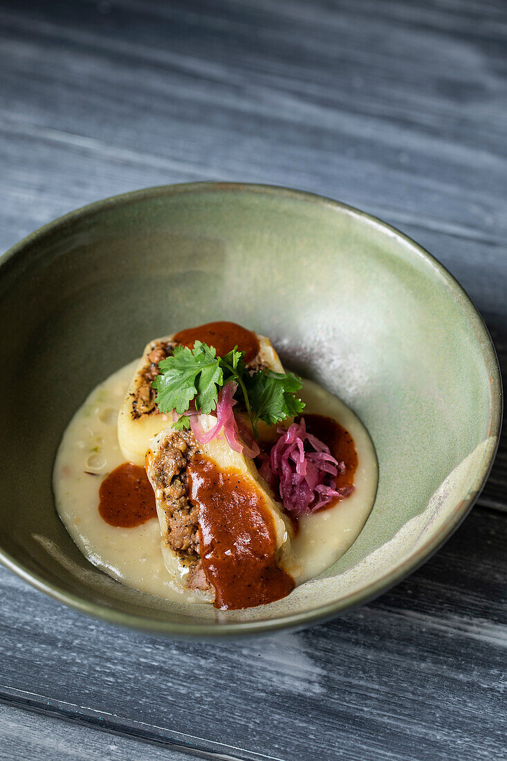 Mayan dish made of cheese stuffed with ground beef and served under white sauce called kol with pickled onion and parsley