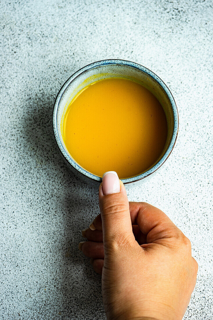 Top view of spiced turmeric moon milk drink in grey ceramic cup on stone table