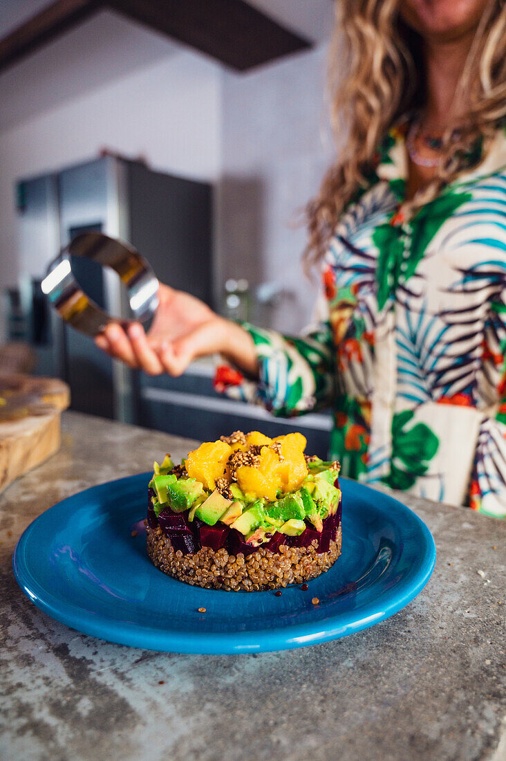 Soft focus of delicious layer salad made of quinoa and beet with avocado and mango and served on plate in kitchen at home