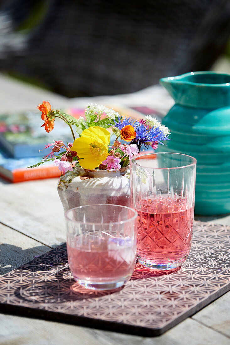 Rhubarb juice and colorful bouquet of flowers on an outdoor table