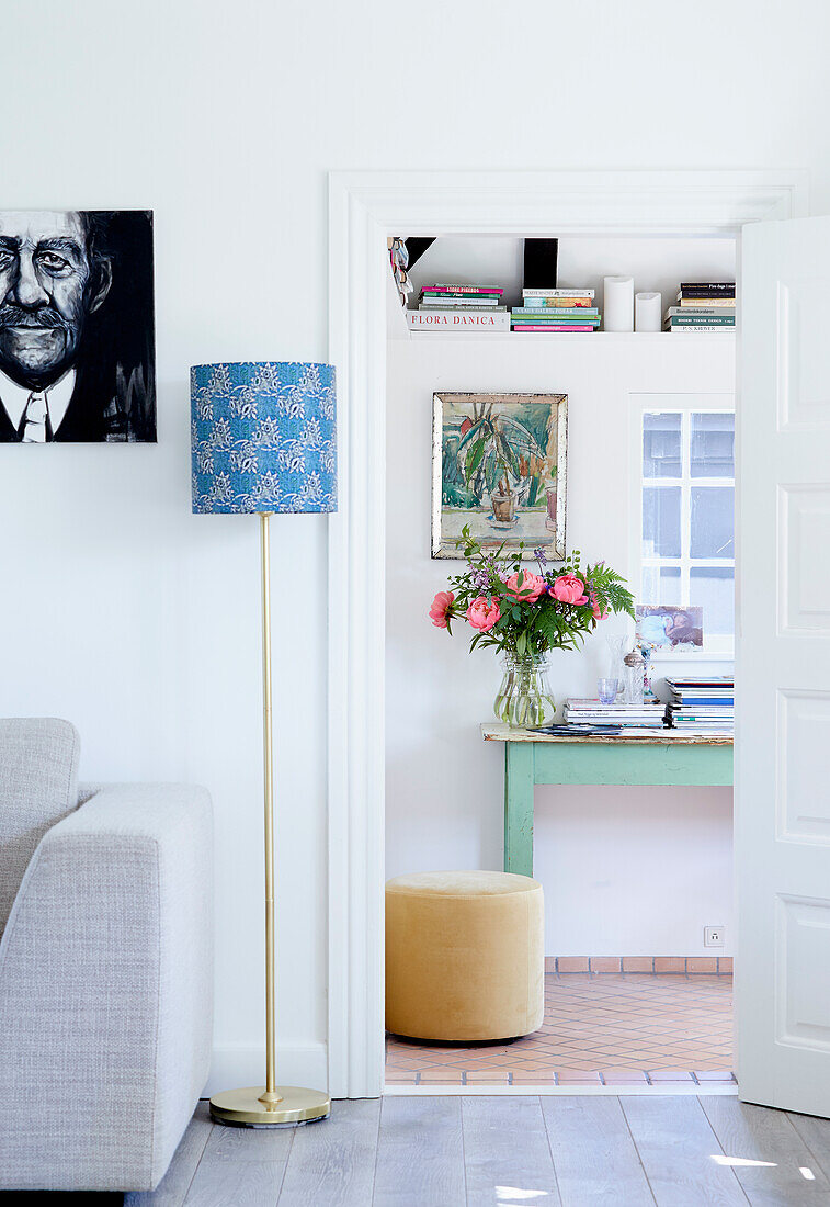 Open doorway next to a sofa and floor lamp, looking into the home office