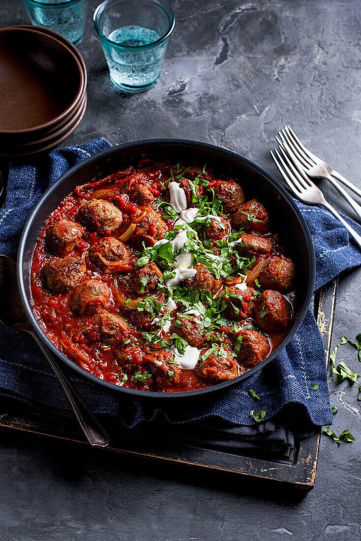 Meatballs with tomato-harissa sauce, coriander, tahini and lemon yoghurt