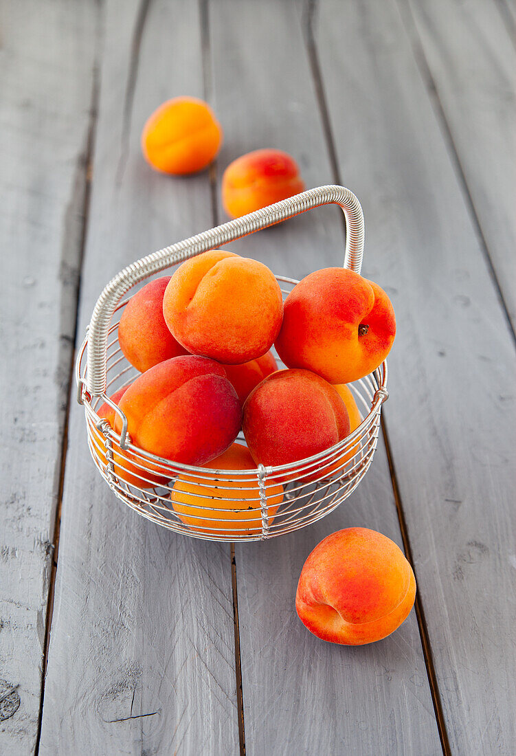 Apricots in wire baskets and on a grey wooden background