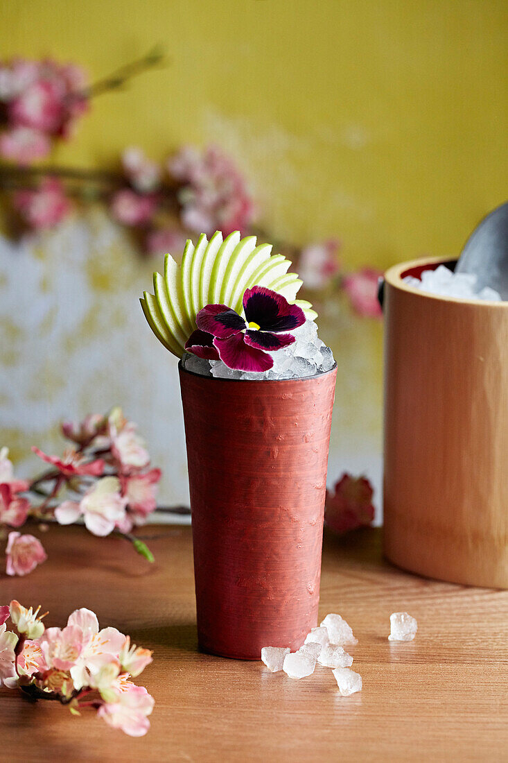 Cocktail garniert mit Apfel und Blüte