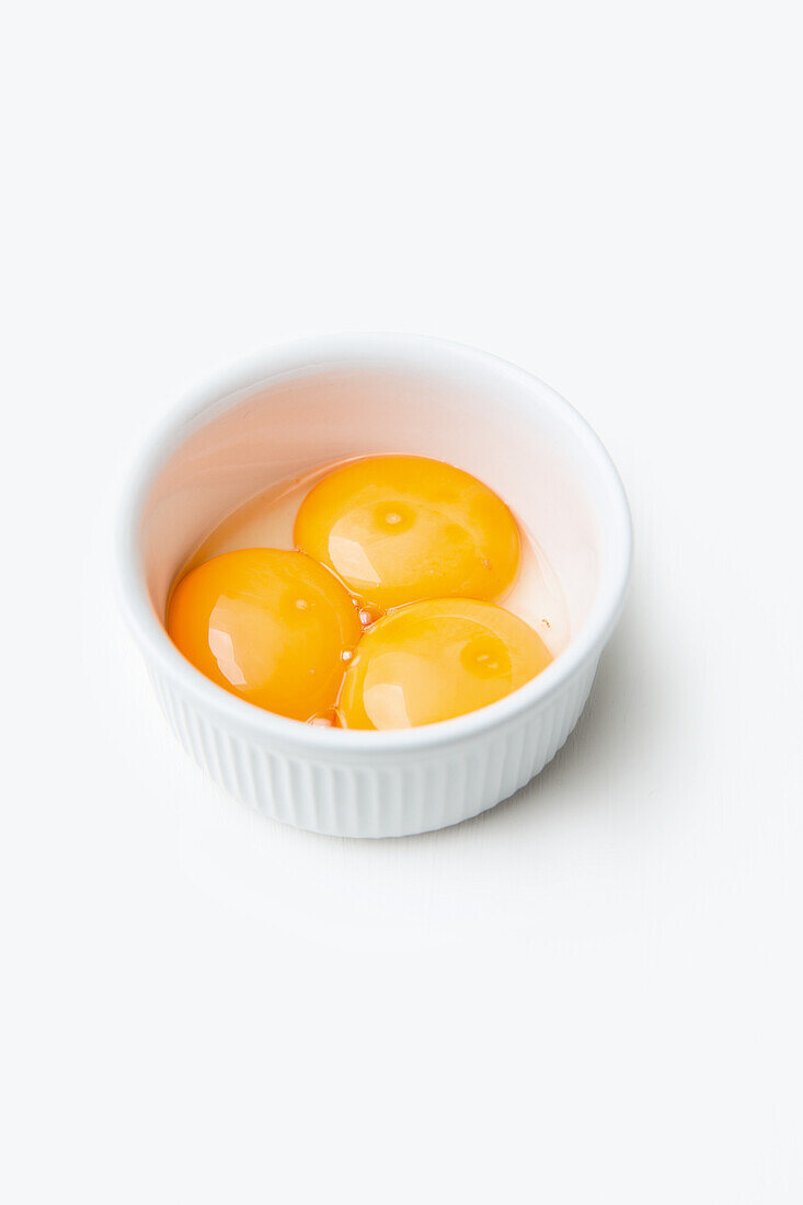 Three egg yolks in a small bowl