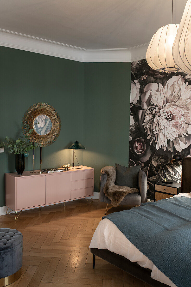 Angeleuchtete rosa Sideboard vor grüner Wand und Blumentapete im Schlafzimmer