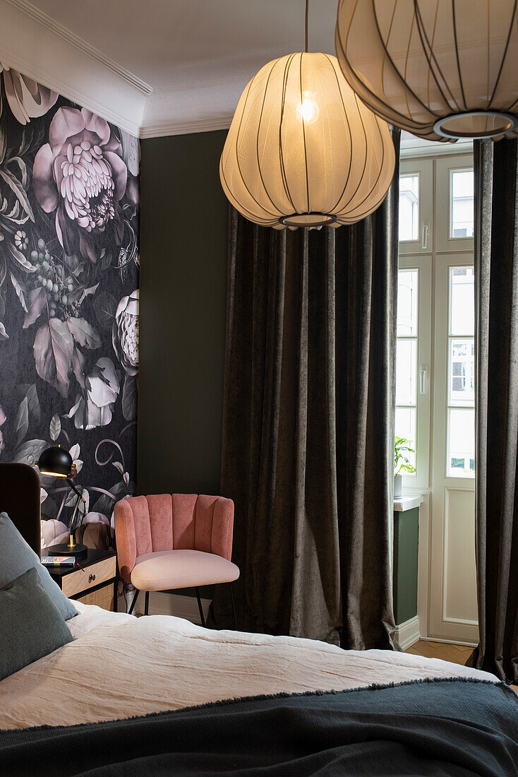 Upholstered chair in the corner of a room with green wall and floral wallpaper