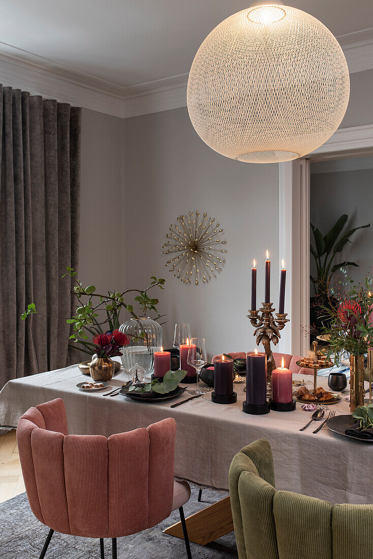 Festively laid Christmas table with candles, velvet upholstered chairs around the table