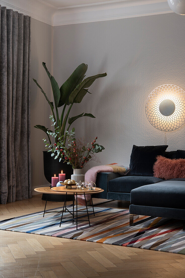 Wall mounted light above velvet sofa, side tables, and indoor plant