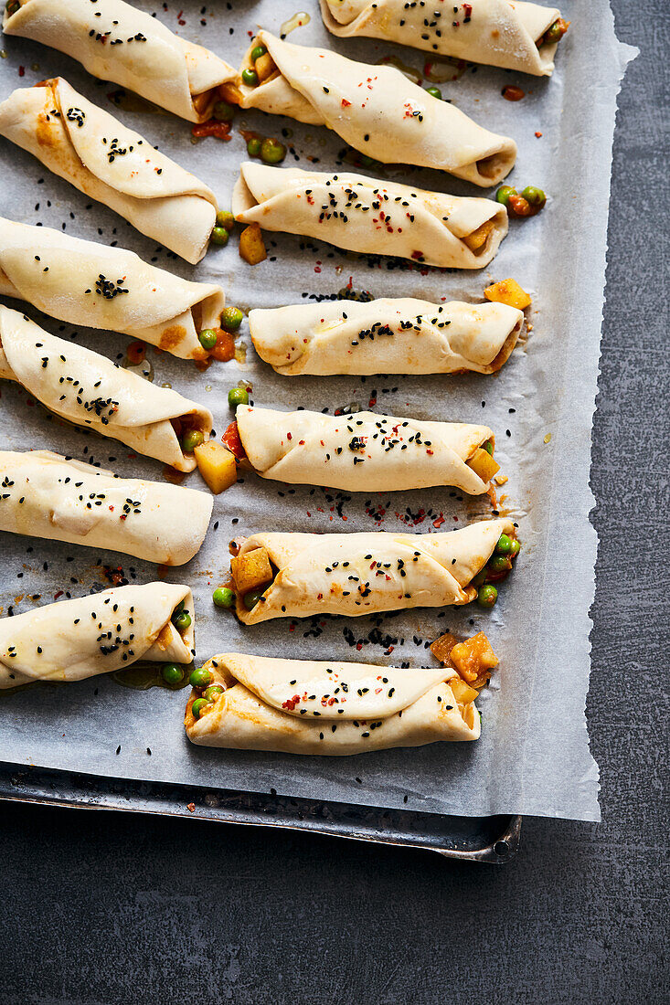 Naan bread rolls with a potato curry filling on a baking tray