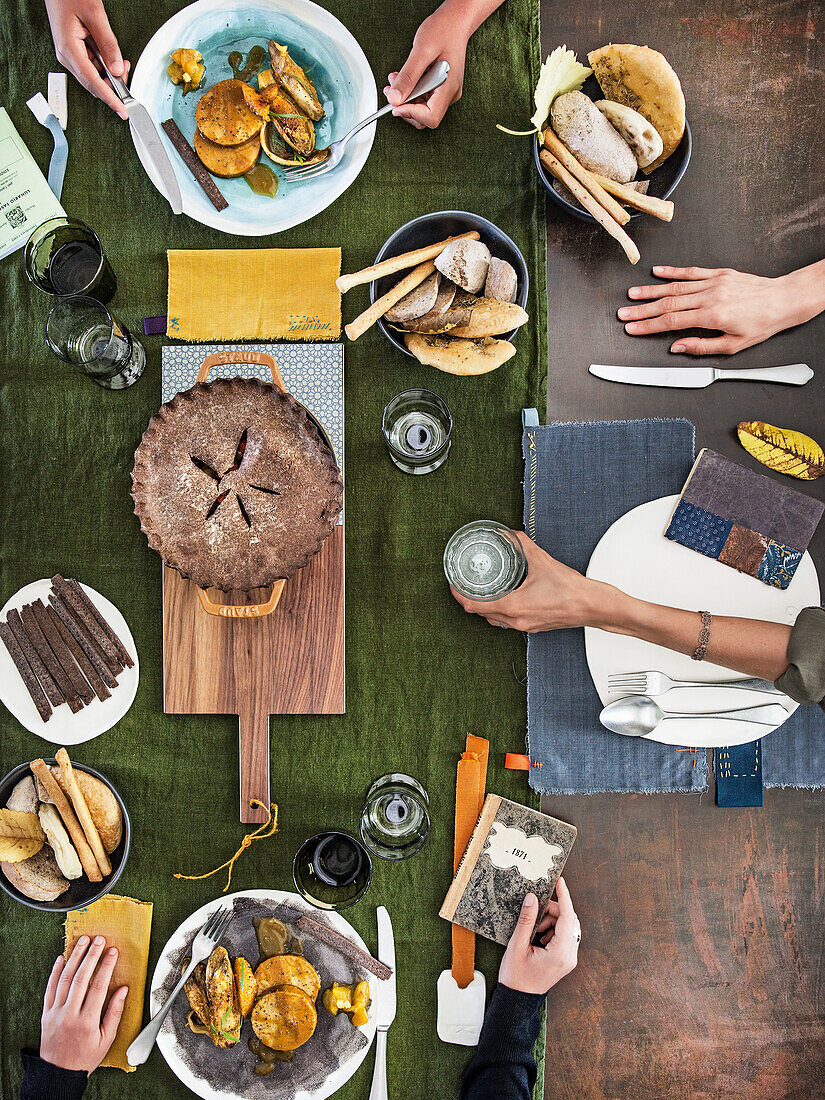 Gedeckter Tisch mit Wurzelgemüse-Pie in schwarzer Reiskruste und veganem Tofubraten