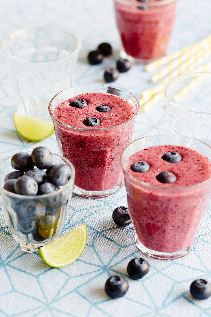 Red berry smoothie with blueberries and lime in glasses