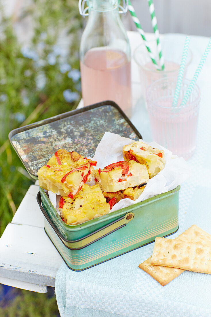 Potato tortilla with peppers in vintage tin for picnic