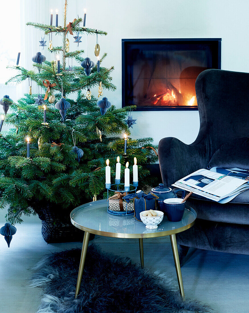 Coffeetable mit Kerzen, blauer Samtsessel und Weihanchtsbaum vor Kamin