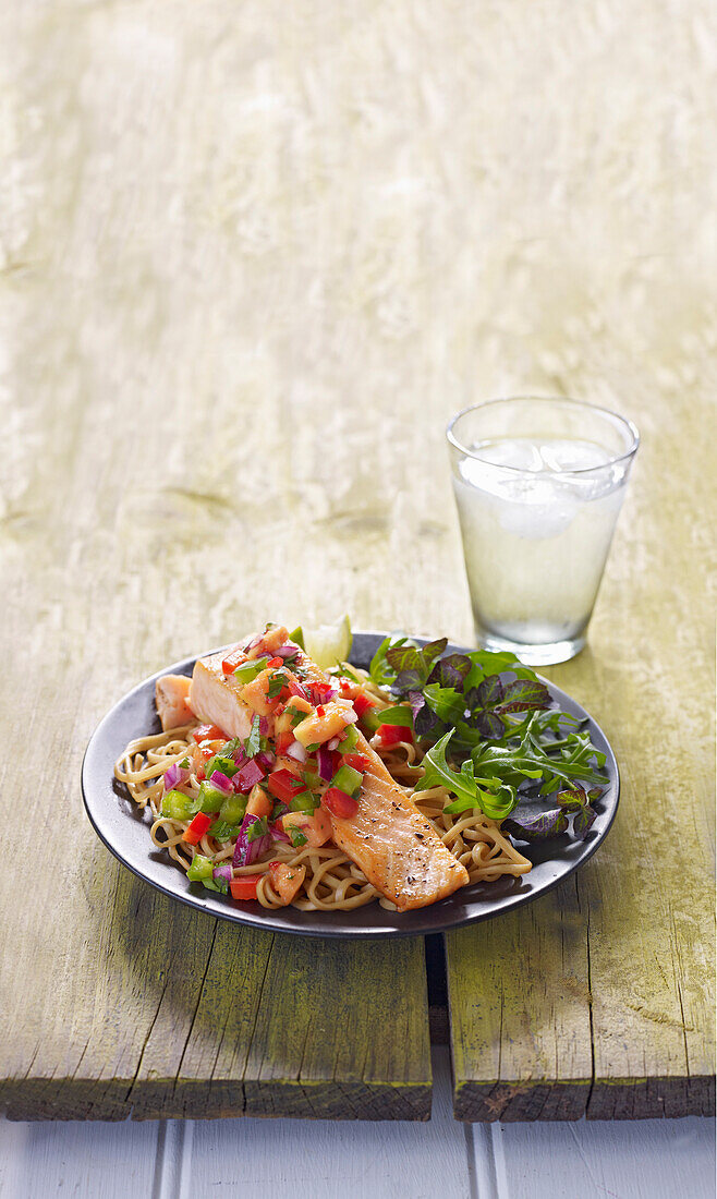 Summer salmon dish with papaya salsa served on noodles and with leaf salad