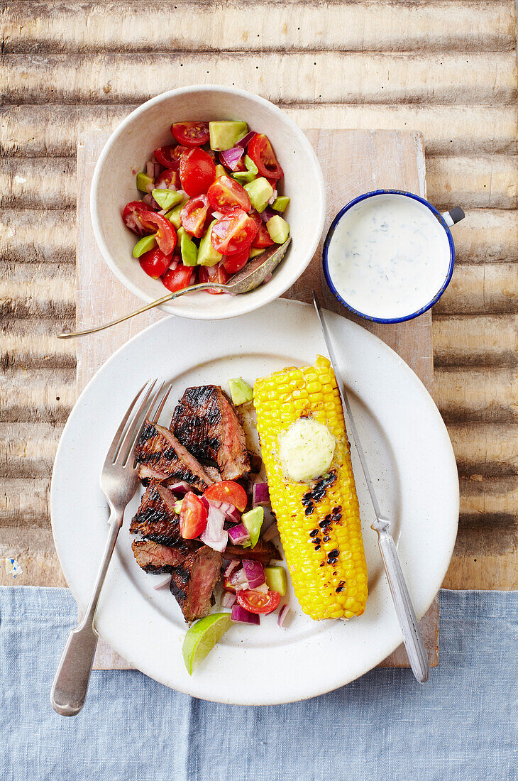 Grilled steak with tomato salad and BBQ corn